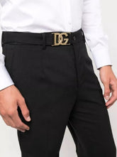 A pair of black Dolce & Gabbana men's pants with a gold logo belt, suitable for business or formal occasions.